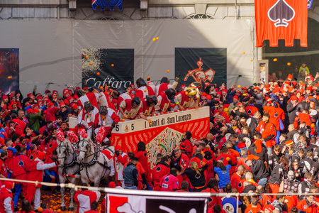 Ivrea, Italy - February 19, 2023: Battle of the Oranges scene of the town square (Piazza di Citta), with fighters and crowd, part of the historical carnival of Ivrea, Piedmont, Northern Italyのeditorial素材