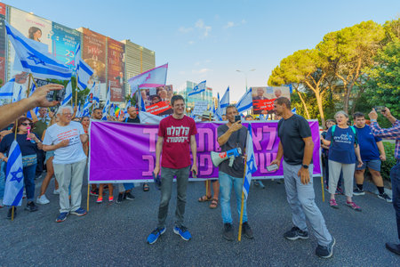 Haifa, Israel - August 05, 2023: People march with various flags and signs, slogan: We shall not...