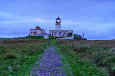 Sunset view of Neist Point Lighthouse, coastal cliffs, and rocks, in the Isle of Skye, Inner Hebrides, Scotland, UKの写真素材