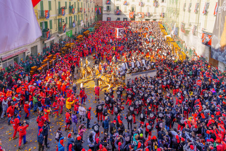 Ivrea, Italy - February 19, 2023: Battle of the Oranges scene of the town square (Piazza di Citta), with fighters and crowd, part of the historical carnival of Ivrea, Piedmont, Northern Italyのeditorial素材