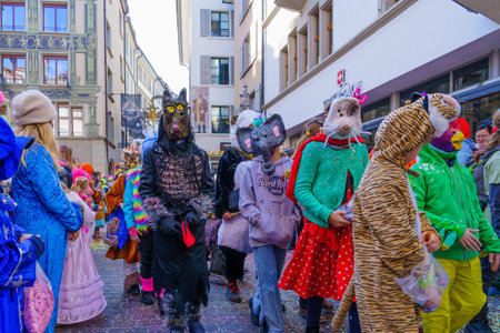 Lucerne, Switzerland - February 21, 2023: Group of participants in costumes march in the streets, and crowd, part of the children parade of the Fasnacht Carnival, in Lucerne (Luzern), Switzerlandのeditorial素材