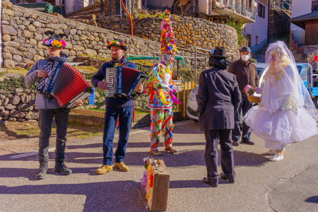 Valfloriana, Italy - February 26, 2022: Carnival participants costumed as bride and groom, and musicians, in the Valfloriana carnival, Trentino, Northern Italyのeditorial素材