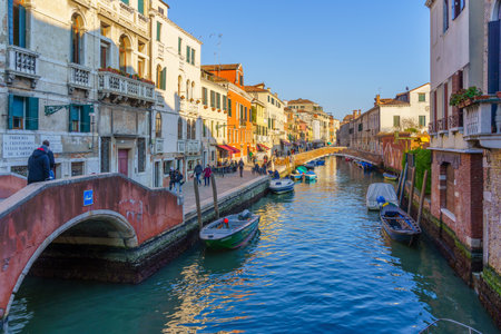 Venice, Italy - February 28, 2022: View of the Rio dell Misericordia, with buildings, boats, bridges, locals, and visitors, in Venice, Veneto, Northern Italyのeditorial素材