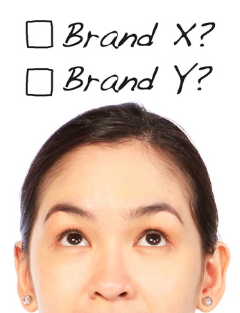 A young woman thinking of which brand to choose or buy の写真素材