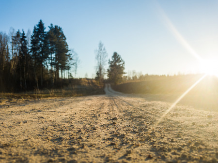 Closeup Photography of a Countryside Road in Sunny Winter Day with a Little Snow on the Sides an Trees in the Backgroundの写真素材