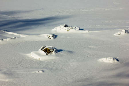 Small Rocks Partly Frozen In River on a Sunny Winter Day, Partly Covered With a Snowの写真素材