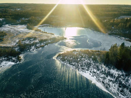 Aerial Drone Photograph of a Partly Frozen Lake Surrounded with Beautiful Winter Colors of the Fields and Forestの写真素材
