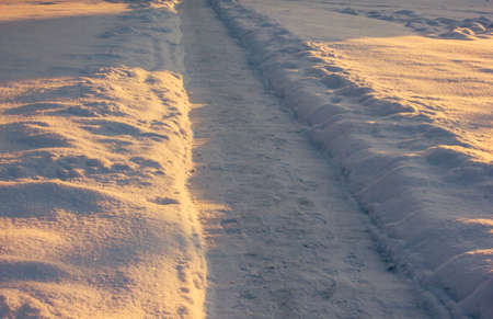 Snowy Footpath in a Countryside with the Sun Rays Gloving over itの写真素材