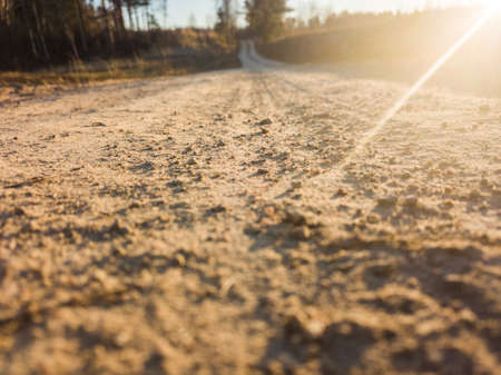 Closeup Photography of a Countryside Road in Sunny Winter Day with a Little Snow on the Sides an Trees in the Backgroundの写真素材