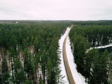 Aerial Drone Photography of a Road in Winter, Between Woods with a Snow on a Cloudy Day