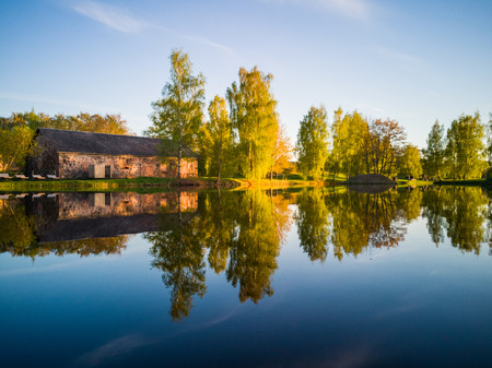 Beautiful Tree Reflection in the Lake on a Sunny Spring Day - Autumn Colours. With a Clear Blue Skies Above them - Symmetric Reflectionの写真素材