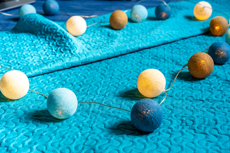Christmas Decoration Light Balls Laying on Mattress with Turquoise Backgroundの写真素材