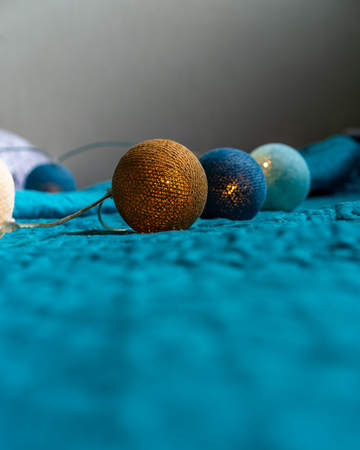 Christmas Decoration Light Balls Laying on Mattress with Turquoise Backgroundの写真素材