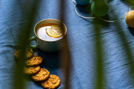 Tea with Lemon and Cookies with Chocolate Laying on Mattress - Blurred Turquoise Cover in Background with Pillowの写真素材