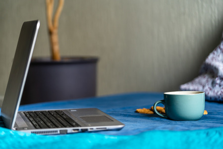Tea with Lemon and Cookies with Chocolate Laying on Mattress - Grey Laptop Besides it, Blurred Turquoise Backgroundの写真素材