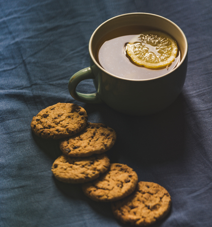 Tea with Lemon and Cookies with Chocolate Laying on Mattress - Blurred Turquoise Cover in Background with Pillow, Vintage Look Editの写真素材