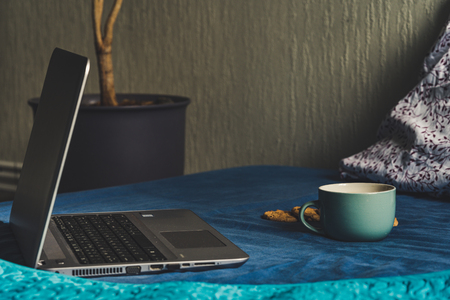 Tea with Lemon and Cookies with Chocolate Laying on Mattress - Grey Laptop Besides it, Blurred Turquoise Background, Vintage Look Editの写真素材