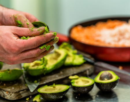 Male Chef Pealing Avocado for  Wedding Meal - Kitchen Set with Isolated Action, Only Chef`s Handsの写真素材