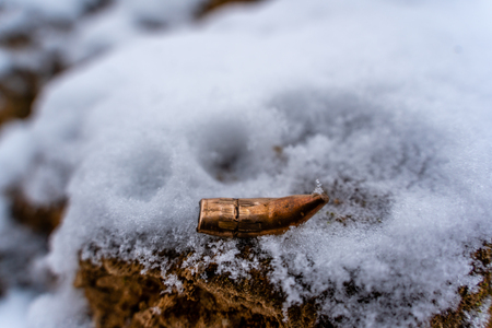 Bent Bullet After Being Shot on The Snowy Sand Backgroundの写真素材