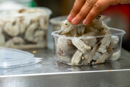 Female Chef Putting Fresh Shrimps into Plastic Container - Kitchen Setの写真素材
