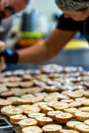 Male and Female Chef Spreading the Sauce on the Sliced Bread Spread on a Table for Small Burgers - Kitchen Setの写真素材