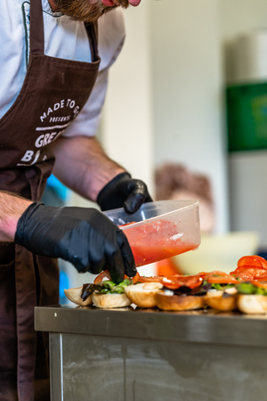Male Chef Putting Ingredients of Burgers on a Sliced Bread Spread on a Table - Kitchen Setの写真素材