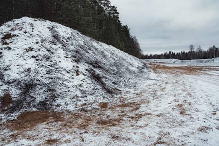 Car Tire Marks on an Empty Field Covered With Snow, Wood in the Background - Cloudy Day, Vintage Film Lookの写真素材