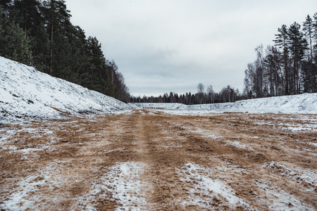 Car Tire Marks on an Empty Field Covered With Snow, Wood in the Background - Cloudy Day, Vintage Film Lookの写真素材