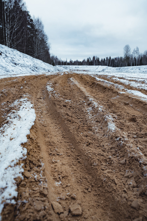Car Tire Marks on an Empty Field Covered With Snow, Wood in the Background - Cloudy Day, Vintage Film Lookの写真素材
