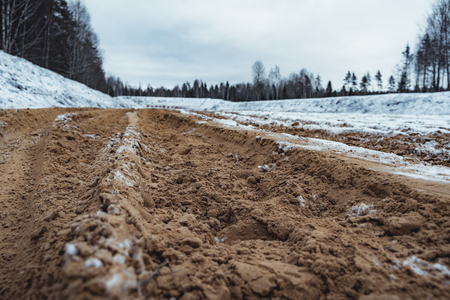 Car Tire Marks on an Empty Field Covered With Snow, Wood in the Background - Cloudy Day, Vintage Film Lookの写真素材