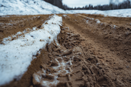 Car Tire Marks on an Empty Field Covered With Snow, Wood in the Background - Cloudy Day, Vintage Film Lookの写真素材