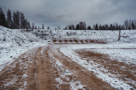 Car Tire Marks on an Empty Field Covered With Snow, Wood in the Background - Cloudy Day, Vintage Film Lookの写真素材