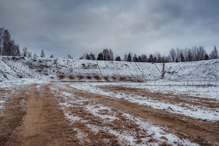 Car Tire Marks on an Empty Field Covered With Snow, Wood in the Background - Cloudy Day, Vintage Film Lookの写真素材