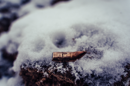 Bent Bullet After Being Shot on The Snowy Sand Background - With Ballistic Marks, Vintage Film Lookの写真素材