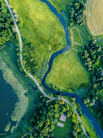 Aerial Photo of Road going by the River under the Trees, Top Down View in Early Spring on Sunny Day - Concept of Peaceful Life in Countryside in Harmonyの写真素材