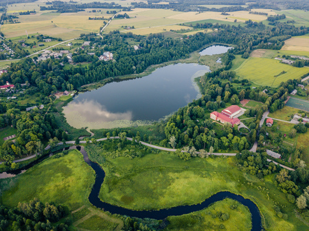 Aerial Photo of Countryside Village Between Trees and with Big Blue Lake Besides it in Early Spring on Sunny Day - Concept of Peaceful Life in Countryside in Harmonyの写真素材