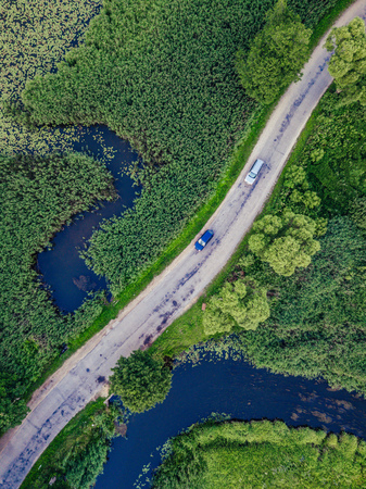 Aerial Photo of Car Driving on the Road going by the River under the Trees, Top Down View in Early Spring on Sunny Day - Concept of Peaceful Life in Countryside in Harmony and Traveling, Freedomの写真素材