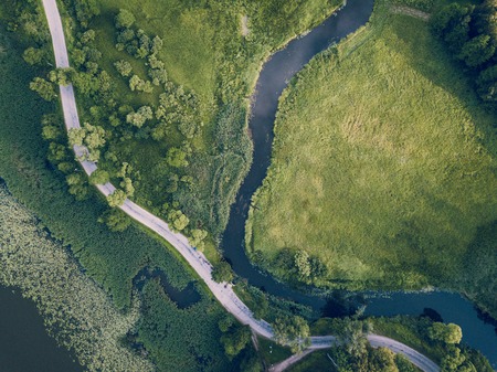 Aerial Photo of Road going by the River under the Trees, Top Down View in Early Spring on Sunny Day - Concept of Peaceful Life in Countryside in Harmony, Vintage Film Lookの写真素材