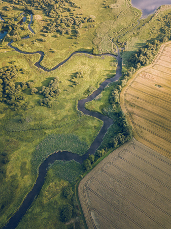 Aerial Photo the River Flowing Between Yellow and Green Agriculture Fields in Early Spring on Sunny Day - Concept of Peaceful Life in Countryside in Harmony and Traveling, Freedom, Vintage Film Lookの写真素材