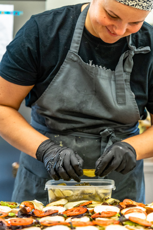 Female Chef Putting Ingredients of Burgers on a Sliced Bread Spread on a Table in Black Gloves - Concept of the Hard Working Person and the Hygiene in the Kitchenの写真素材