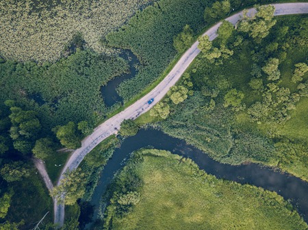 Aerial Photo of Car Driving on the Road going by the River under the Trees, Top Down View in Early Spring on Sunny Day - Concept of Peaceful Life in Countryside in Harmony and Traveling, Freedomの写真素材