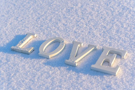 Isolated Word "Love" from Wooden Pieces in the Snow on Sunny Winter Day with White Background - Concept of Love, Happiness and Joy on Valentines Dayの写真素材