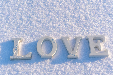 Isolated Word "Love" from Wooden Pieces in the Snow on Sunny Winter Day with White Background - Concept of Love, Happiness and Joy on Valentines Dayの写真素材