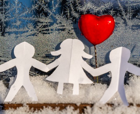 Isolated Chain of Origami Paper Boys and Girls Holding Hands With a Red Heart Between Them and the Hoarfrost on Window in Background - Concept of Love, Happiness and Joy on Valentines Dayの写真素材