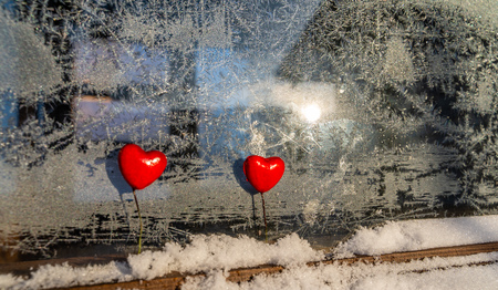 Blurred Read Heart Decorations on the Foreground of Window with Hoarfrost - Abstract Background with the Space for Text, Concept of Love and Happiness on Valentines Dayの写真素材