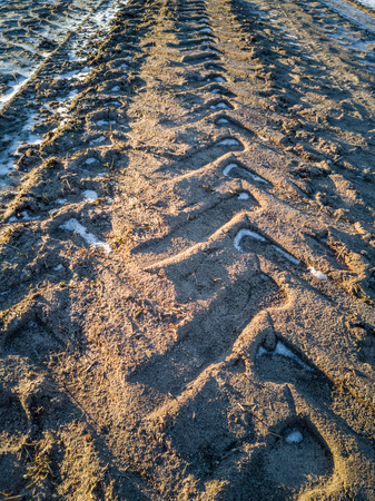 Empty Countryside Landscape in Sunny Winter Day with Snow Partly Covering the Ground, Tire Marks on The Roadの写真素材