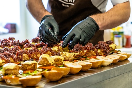 Odziena / Latvia - August 24th, 2018: Male Chef Putting Ingredients of Burgers in Black Gloves - Concept of the Hard Working Person and the Hygiene in the Kitchen, Partly Blurred Foregroundの写真素材