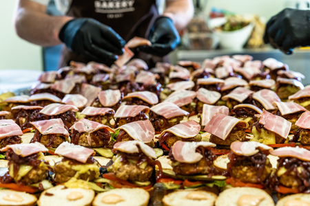 Odziena / Latvia - August 24th, 2018: Male Chef Putting Ingredients of Burgers in Black Gloves - Concept of the Hard Working Person and the Hygiene in the Kitchen, Partly Blurred Foregroundのeditorial素材