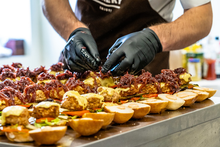 Odziena / Latvia - August 24th, 2018: Male Chef Putting Ingredients of Burgers in Black Gloves - Concept of the Hard Working Person and the Hygiene in the Kitchen, Partly Blurred Foregroundのeditorial素材
