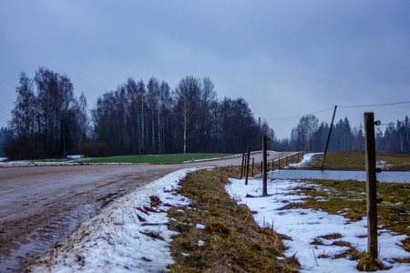 Empty Countryside Landscape in Cloudy Winter Day with Snow Partly Covering the Ground and Fog - Concept of Sadness and Lonelinessの写真素材